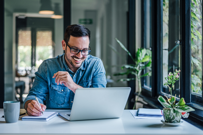 Happy man making plan while working on laptop at home