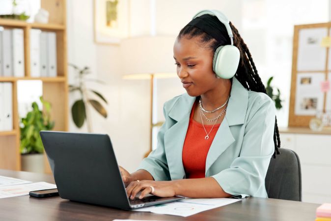Woman with headphones using laptop and typing