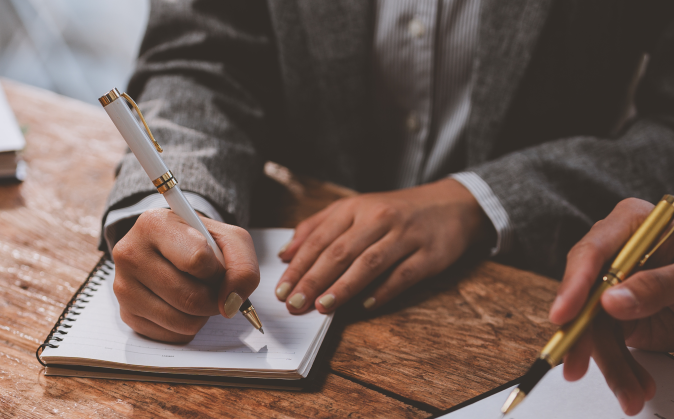 Two guys writing a legal document with a notepad and pen