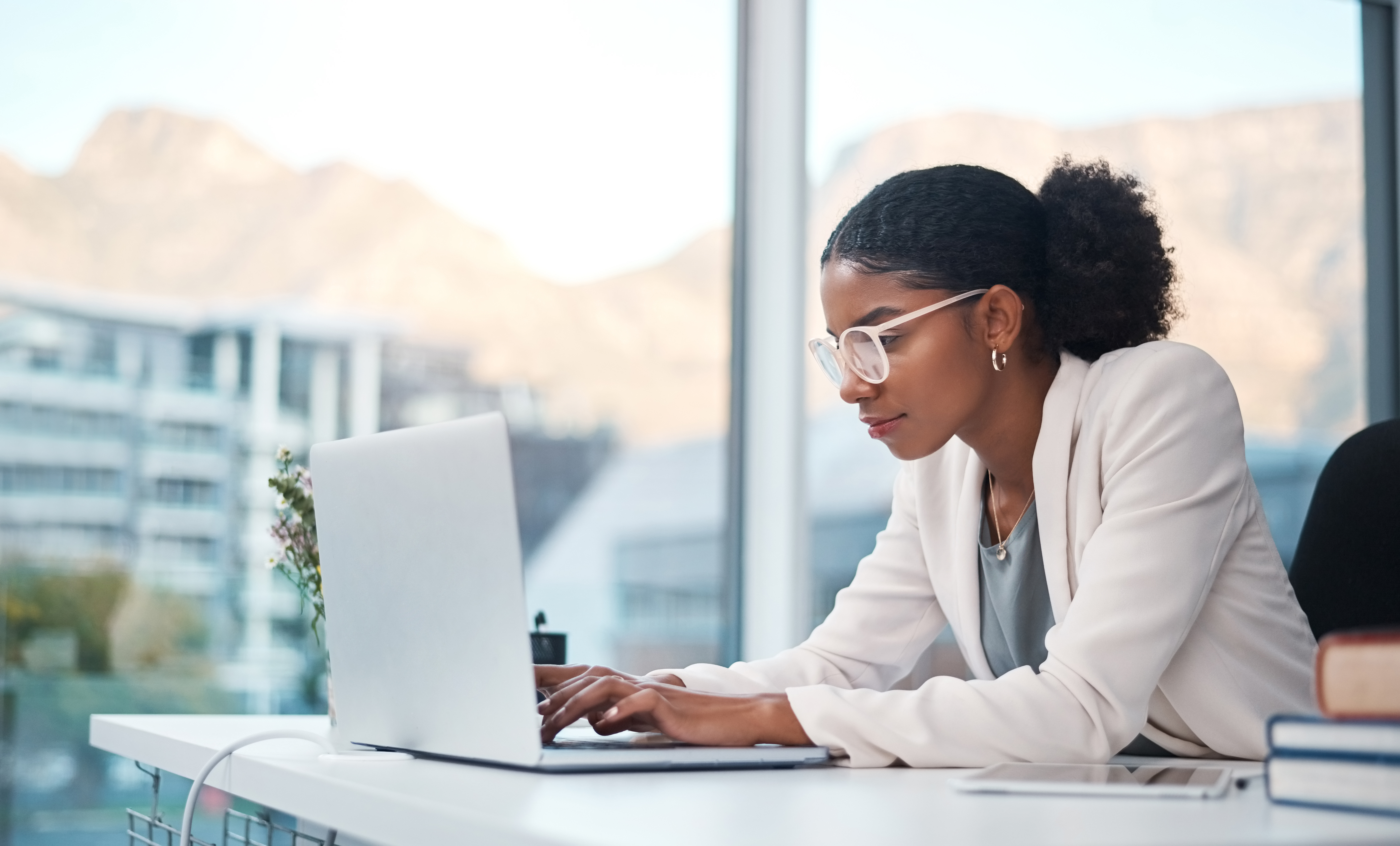 Woman typing on a laptop and doing online research while working in an office.