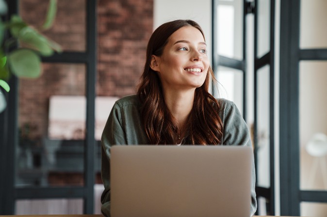 Woman with laptop looking outside smiling