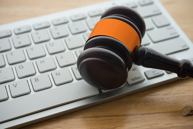 Judge hammer gavel on computer keyboard wooden table background. Online internet crime and scammer, social media law and defamation law concept.
