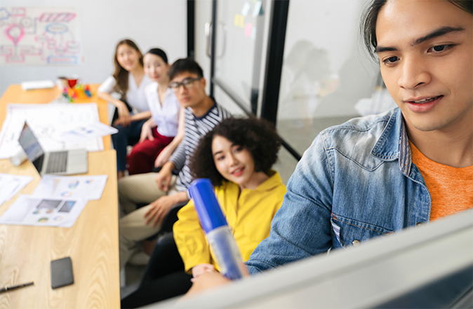 Students sitting in a conference room writing on a whiteboard