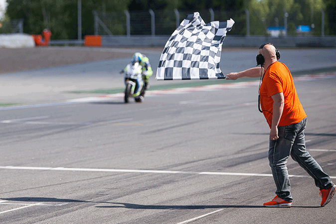 Man waving a checkered flag at end of motorcycle race