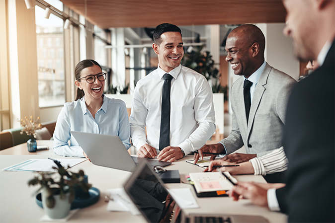Four professional coworkers around table laughing