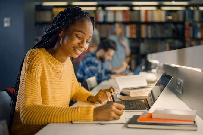 Female student studying on laptop in a library