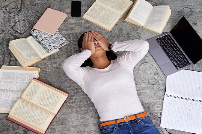 High angle shot of an unrecognizable young female student looking stressed while studying in the library.