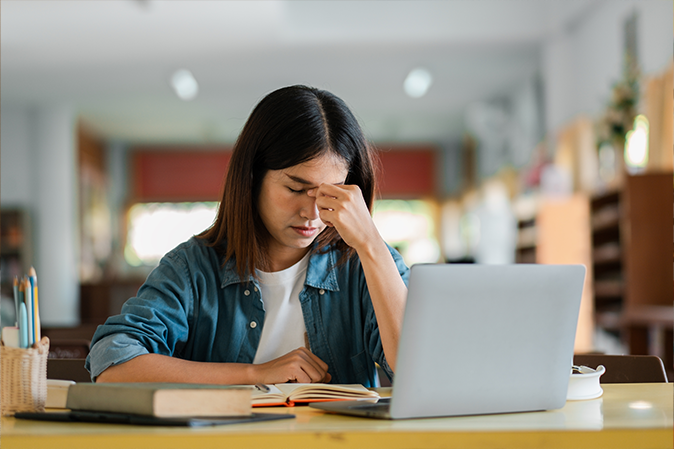 young woman stressed while studying on laptop