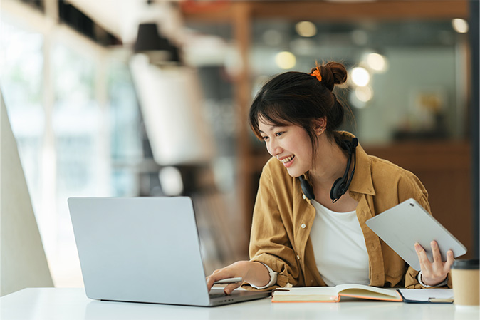 Young woman smiling at her desk typing on a laptop