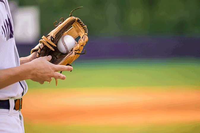 Baseball player with a ball in a glove at a baseball stadium