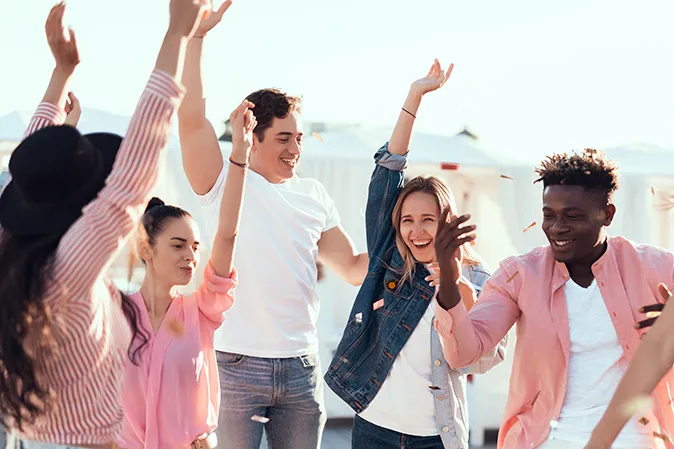 Bunch of young people dancing and jumping in celebration