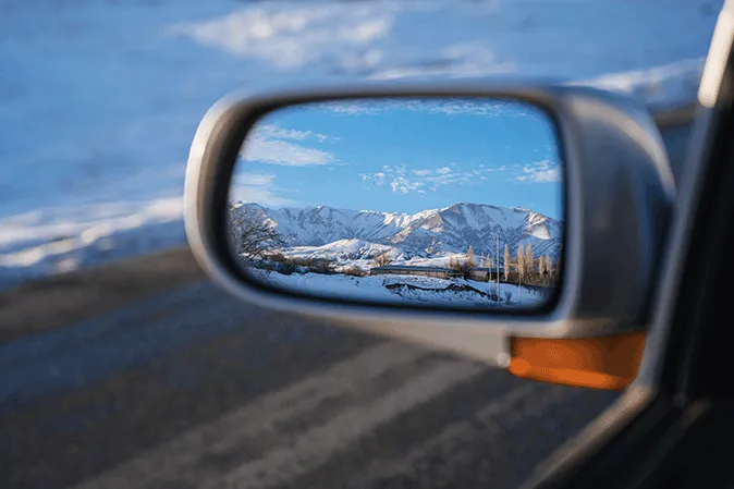 Car side mirror showing a view of the mountains