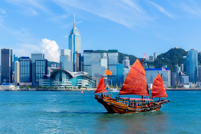 Sailing ship in a chinese harbor with cityscape behind it