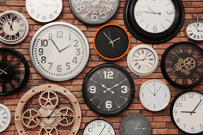 Bunch of clocks hanging on a brick wall