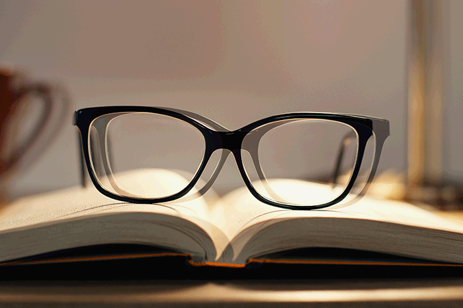 Double vision view of eyeglasses sitting on an open book