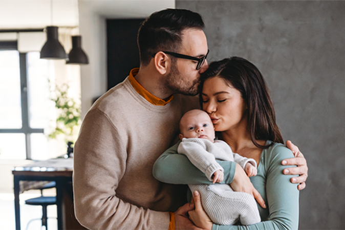 Young couple in their home holding an infant