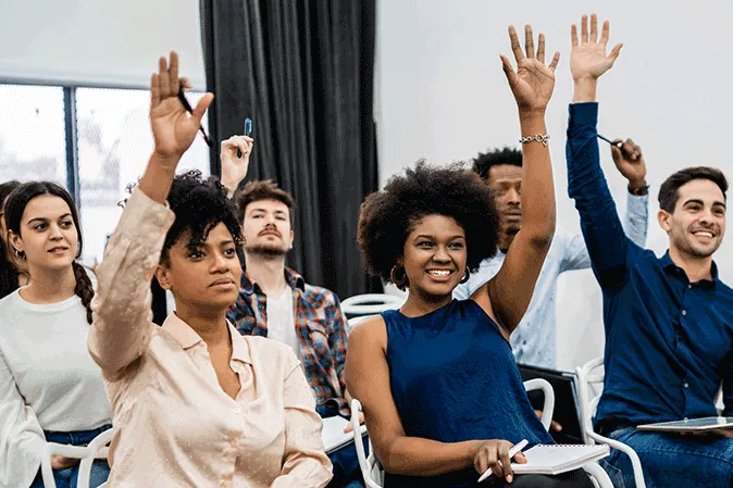 Group of students raising their hands in class