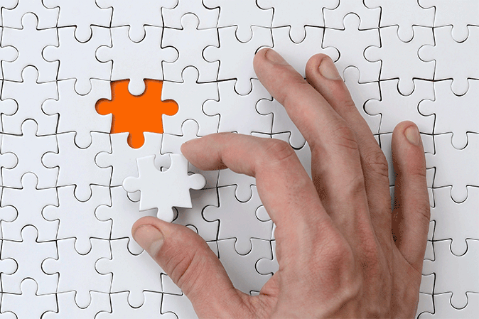 Hand placing a piece into a puzzle