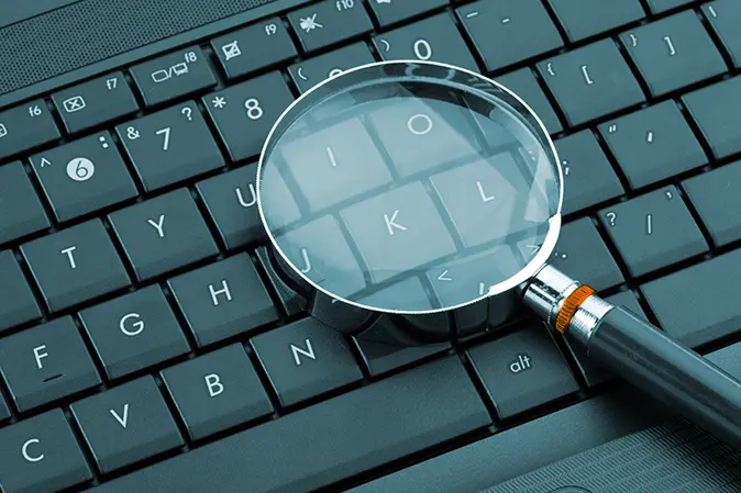 Magnifying glass laying on top of a keyboard