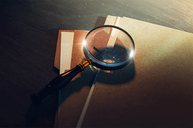 Magnifying glass laying on top of folders of files