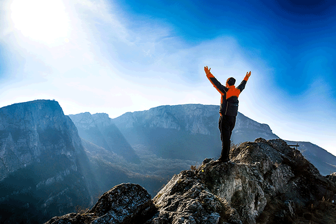 Man celebrating reaching the summit of a mountain