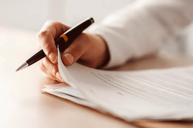 Man holding a pen while looking at a document