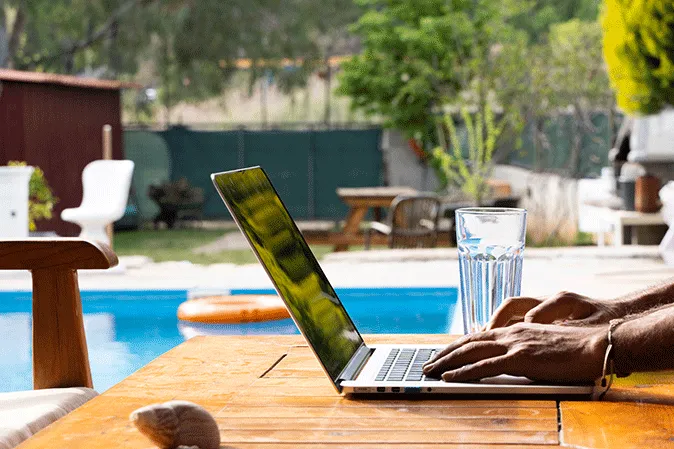 Man typing on his laptop sitting by the pool