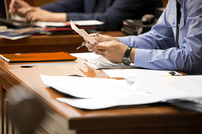 Man sitting at a table in a courtroom with paperwork