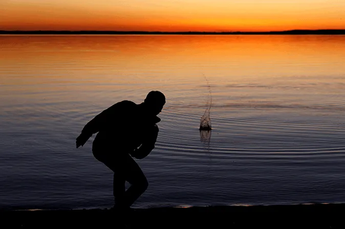 Man skipping rocks on a lake