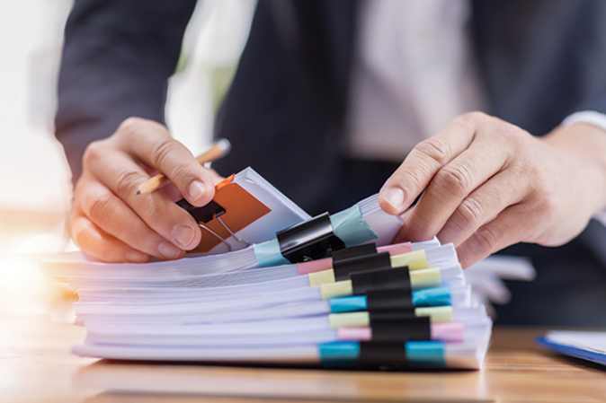 Man working through a pile of clipped documents