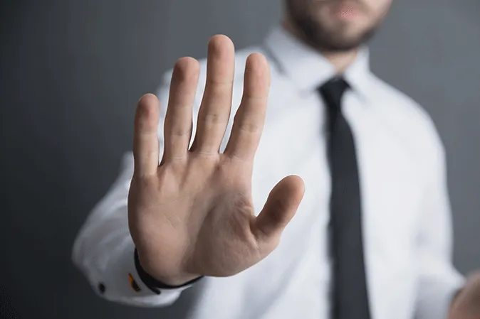 Man wearing a shirt and tie while holding up his hand signaling stop