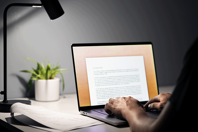 Man sitting at desk typing an essay on laptop