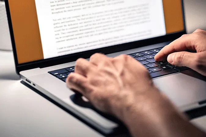 Man typing up a paper on a laptop