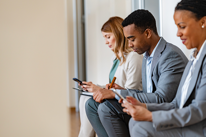 Three people filling out applications while waiting for a job interview