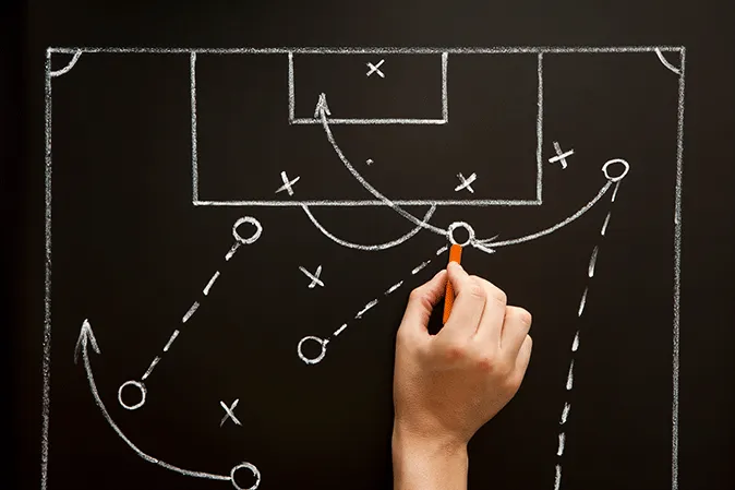 Person drawing sports game strategy on a chalkboard
