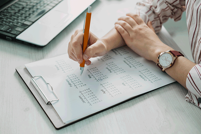 Person with a pen looking at a yearly desk calendar