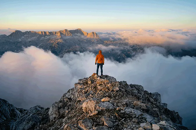 Person standing alone on top of a mountain top