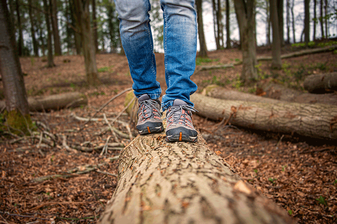 Person walking along a log in the woods