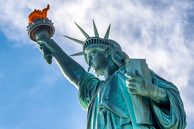 Looking up at the Statue of Liberty with blue sky behind it