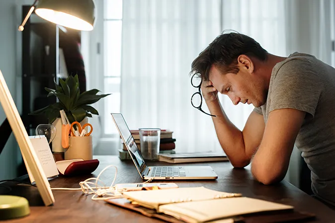 Young man looking stressed out in front of laptop