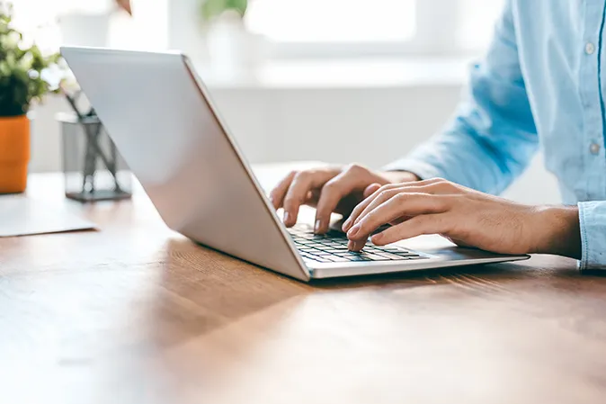 Young man sitting at a desk typing on a laptop