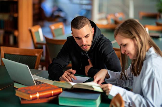 Young man sitting at a desk working with a tutor
