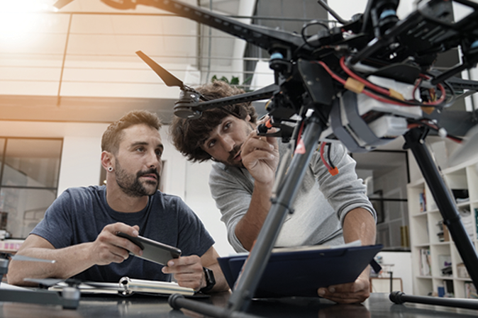 Two young men working together on a drone 