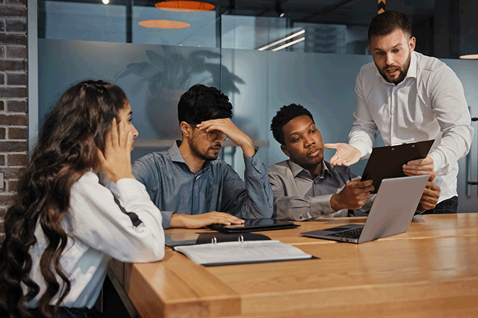 Four young people arguing around a table in an office