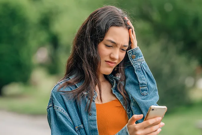 Young woman looking confused at her cell phone