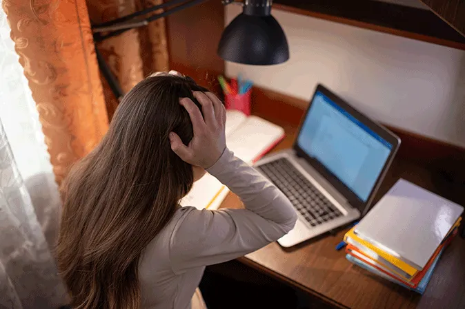 Young woman holding her head in frustration in front of her laptop