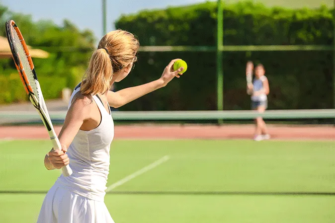 Young woman getting ready to serve a ball in a tennis match