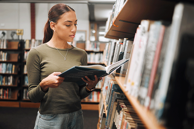 Young woman reading a book in a library