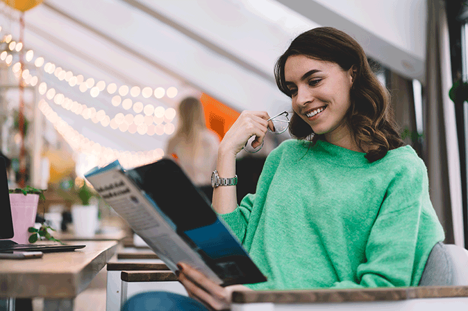 Young woman in a cafe reading a magazine