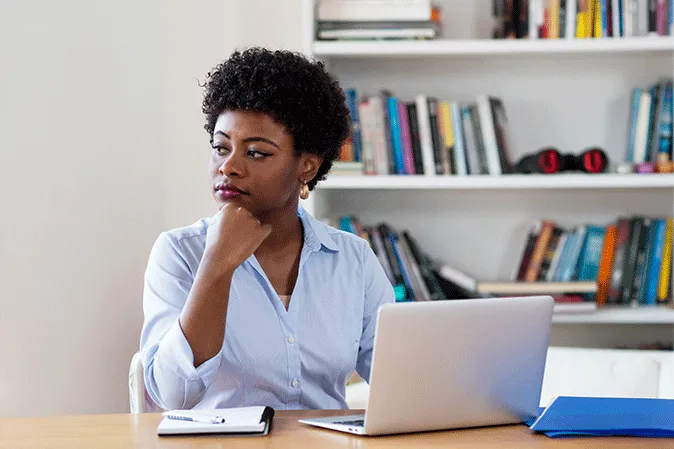 Young woman looking sad sitting at her desk in front of a computer